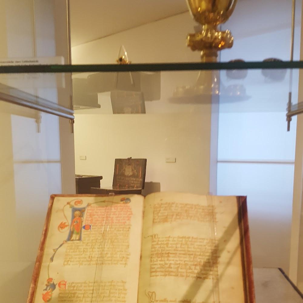 Open book with illuminated manuscript inside a glass case.